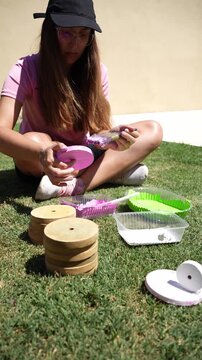 Young woman painting traditional tejo game pieces in garden