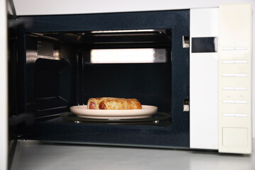 Modern microwave with cooked crepes on countertop in kitchen, closeup
