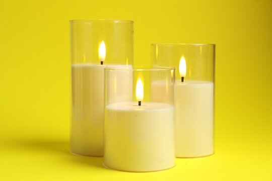 Beautiful LED candles on yellow background, closeup