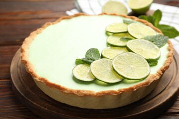 Tasty lime pie with fruit slices and mint leaves on wooden table, closeup © New Africa
