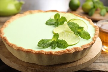 Tasty lime pie with fruit slices and mint leaves on wooden table, closeup © New Africa