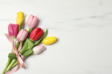 Obraz premium Beautiful colorful tulip flowers on white marble background, top view. Space for text