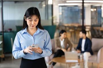 Focused East Asian businesswoman, corporate team member holding smartphone, using business...