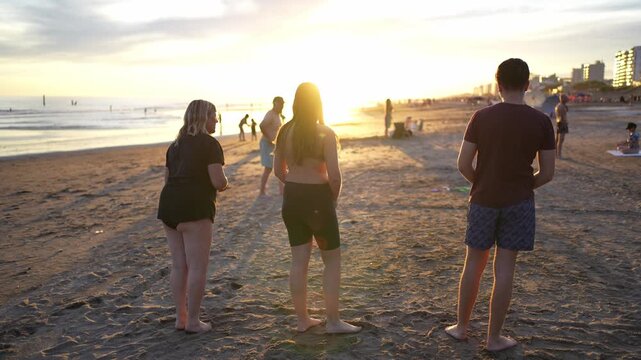 Young friends playing tejo on a sandy beach at sunset