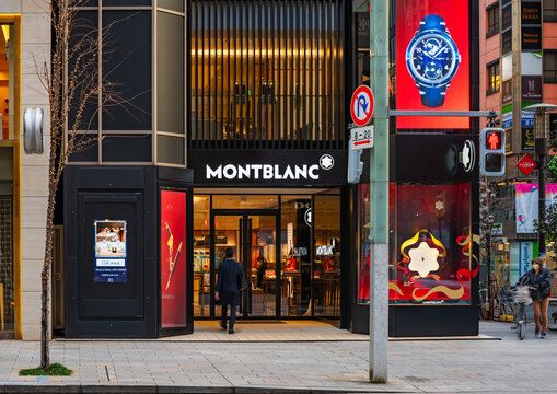 tokyo, ginza - jan 08 2026: A businessman enters the luxury Montblanc flagship store in a bustling Japanese urban district, featuring a prominent watch advertisement and an elegant storefront design.