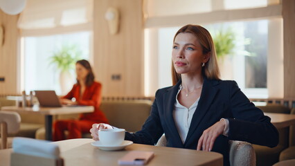 Stylish lady sipping cappuccino in light cafe interior closeup. Confident woman 