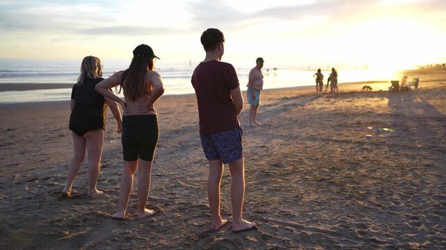 Group of friends playing tejo on the beach at sunset