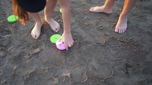People picking up tejo game discs on the beach sand