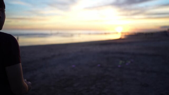 Young man playing tejo game at the beach during sunset
