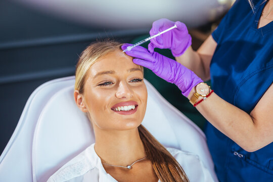 Smiling Young Woman Receiving Botox Injection At Aesthetic Clinic From Professional Nurse