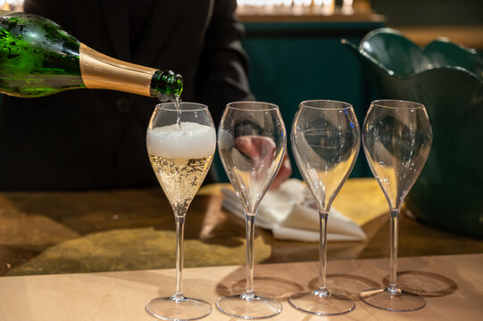 Pouring in glasses of french sparkling wine champagne with little bubbles, tasting wine, celebration, wedding or champagne tour with visit of caves, Reims, France
