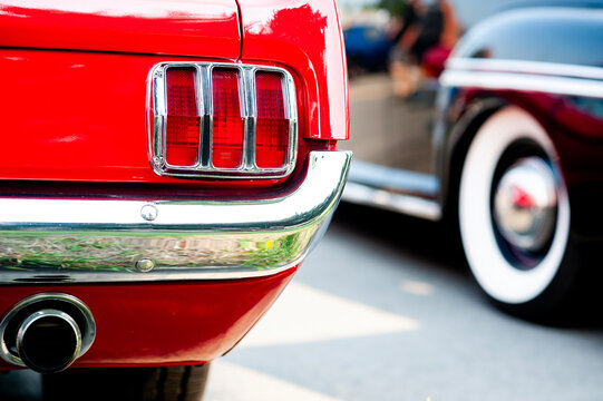 Classic Red Vintage Ford Mustang Taillight Close Up Detail With Chrome Bumper And Dual Exhaust Pipe At Retro American Muscle Car Show Perfect For Nostalgic Automotive History