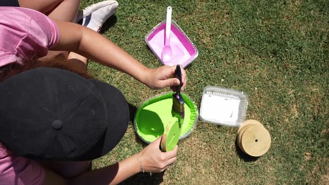 Unrecognizable woman painting a tejo game piece outdoors