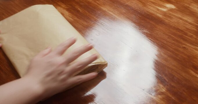 Woman wraps salmon fillet seasoned with salt and pepper in parchment paper for curing. Close-up of homemade salmon preparation process in kitchen, traditional food preservation and cooking at home.