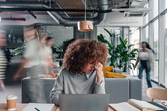 Overwhelmed woman stressing in busy modern office