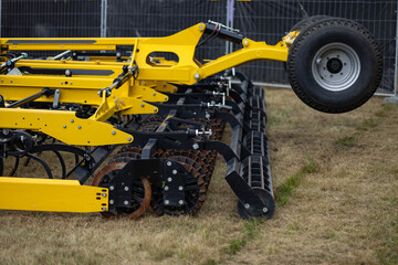 Close up of modern agricultural trailer with heavy duty soil cultivation equipment on field. Farming machinery, agro technology and professional land preparation process in rural environment