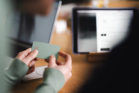 A person holds a payment card near a tablet displaying a website, suggesting online shopping or financial transactions.