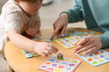Fototapeta premium Mother and her son playing with toys at wooden table indoors, closeup