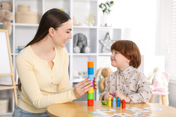 Mother and her son playing with toys on wooden table indoors