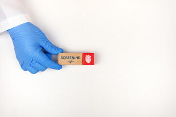 Obraz premium Concept of human well-being, information about the heart, and awareness of early detection. ECG. The cardiologist's hand places wooden cubes with the heart icon.