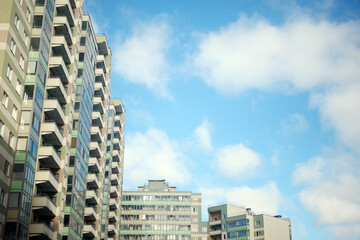 Fototapeta premium Modern urban residential buildings with many balconies standing tall against a bright blue sky with fluffy white clouds overhead