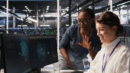 Fototapeta premium Cheerful data center engineers doing fist bump after completing successful AI system deployment. Smiling coworkers celebrating after achieving optimal machine learning model performance, camera A