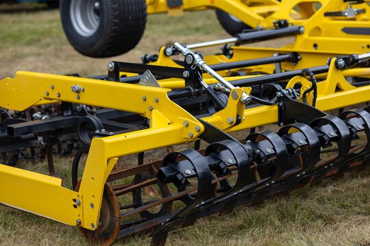 Close up of hydraulic system on yellow agricultural subsoiler with cylinders, hoses and black metal rollers. Modern farming machinery for precise soil preparation in field works