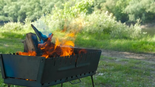 Metal box with burning firewood. A metal box with logs on big red fire in the meadow during holiday time
