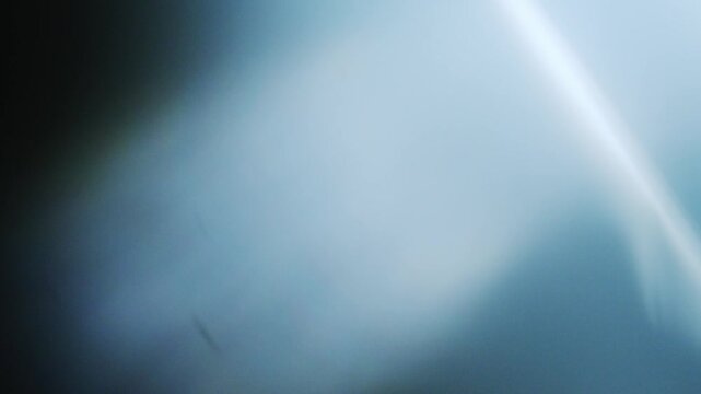 Soft blue light bleeds across a dark, blurred surface