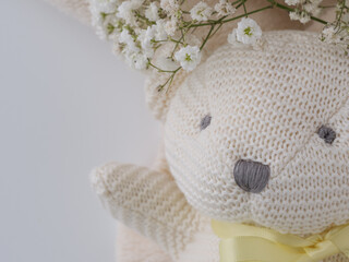 Closeup neutral cream crocheted teddy bear on cozy beige fleece with baby’s breath copy space. Minimal newborn flat lay for gender-neutral baby announcements, showers, nursery branding, and parenting © Andrea