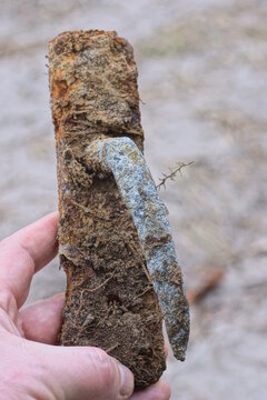hand holding one old dirty rusty brown iron door handle on the street
