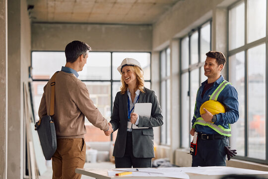Happy architect greeting her client at construction site.
