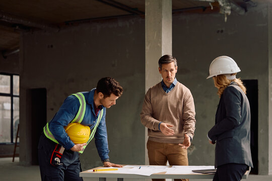 Building contractor talking about project plans with his team at construction site.