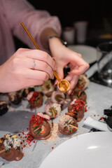 Hands Decorating Chocolate Covered Strawberries With Toppings