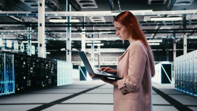 Woman in server farm using laptop to improve electronics optimizations. Female technician walking in data center using notebook to monitor system performance, identifying bottlenecks, camera A