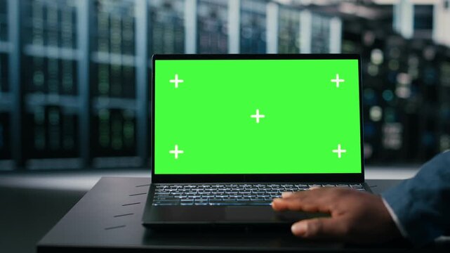 Green screen laptop used by server hub programmer to monitor rigs power consumption. Data center IT expert oversees equipment with mockup notebook, ensuring industry standards compliance, camera B