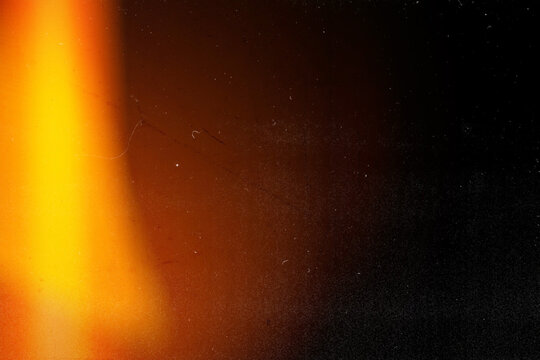 Vintage film burn light leak overlay with heavy dust, scratches, and grain. Vertical yellow and orange edge glow on dark background for retro cinematic video effects and grunge designs.
