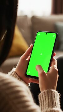Green Screen feminine hand scrolling feed on smartphone with mock up display female is resting at home and checking social media mobile device close over the shoulder footage scene 3 distortion