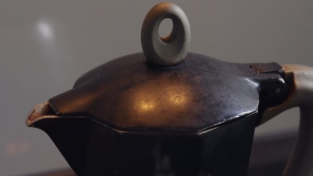 Vintage moka pot with octagonal body and round lid knob on kitchen counter, classic stovetop espresso maker reflecting nostalgic coffee ritual and home brewing culture