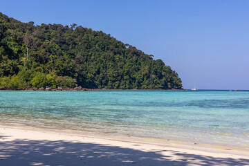 Obraz premium Tropical beach at Koh Surin, Thailand. Clear turquoise water and sandy shore. Lush green hillside in the background. Calm and serene coastal setting.