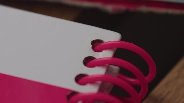Close up of pink spiral notebook binding on desk, detailed macro shot highlighting stationery design texture and vibrant color contrast