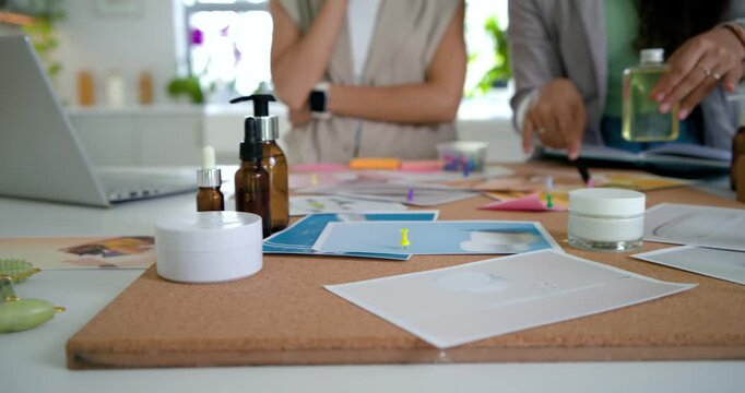 Two African American women reaching, pointing and moving mockups at work table, settling packaging