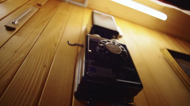Hand lifting receiver of vintage rotary wall telephone inside wooden chalet interior, retro communication device mounted on rustic paneling