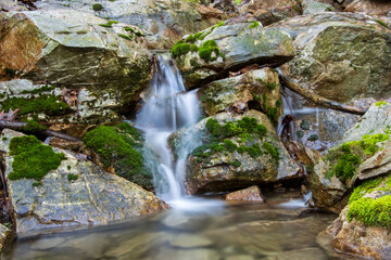 tiny water cascade in the rocks on drying stream with moss and exposed rocks © SurfyArt