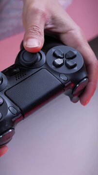 Hands holding controller, pressing buttons on game joystick. Vertical video