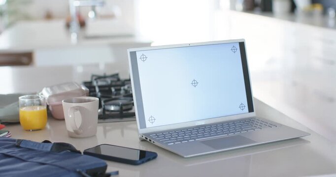 Camera is panning around silver laptop on kitchen island showing tracking marks for insertion
