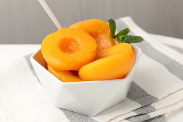 Pickled peaches and mint leaves in bowl on white table, closeup © New Africa