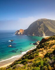 Fototapeta premium Coastal vista of a mountain, beach, and turquoise ocean under a bright sky