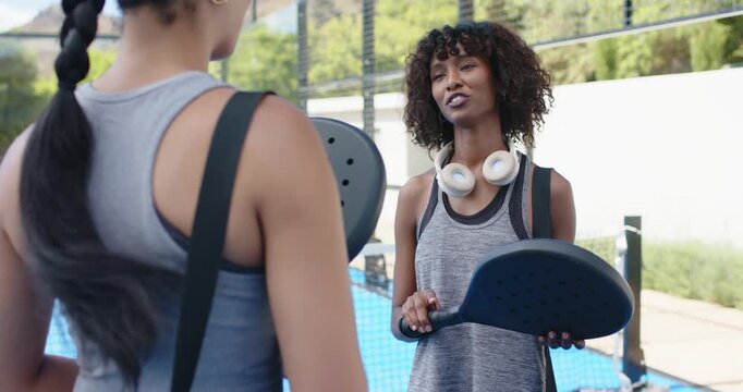 African American women in tank tops meeting, pointing paddle and high-fiving before play on court