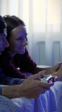 Excited funny couple with wireless controllers playing video game.Vertical video